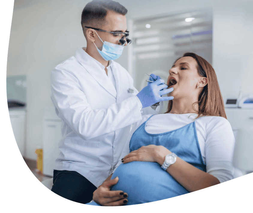 Zubný lekár v maske a rukaviciach vyšetruje pacientku v zubnej ambulancii.